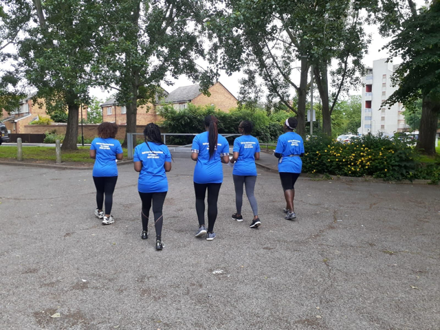 Members of the Thamesmead Delivery Team walking away from the camera, showing off their team t-shirts. 